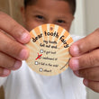 Load image into Gallery viewer, a boy holds a lost tooth token that says Dear Tooth Fairy my tooth fell out and... it got lost, I swallowed it, it fell in the sink, other.